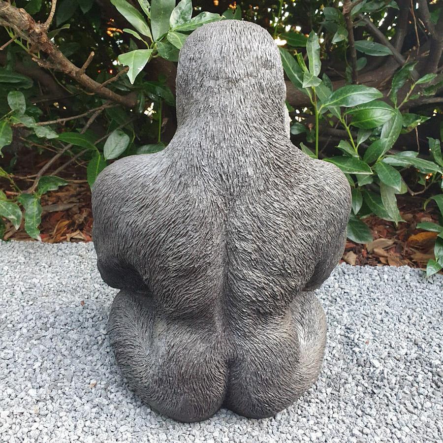 Gorilla sitzt als Gartenfigur von hinten