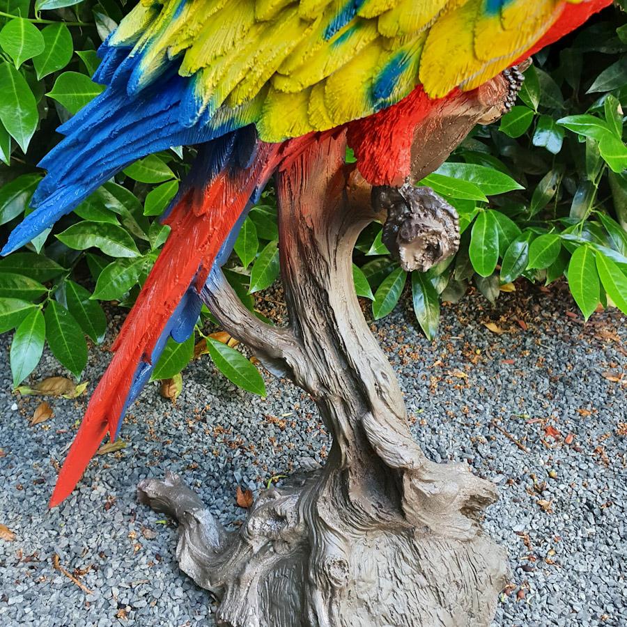 Großer Roter Papagei auf Ast als Gartenfigur Nahaufnahme vom Stamm