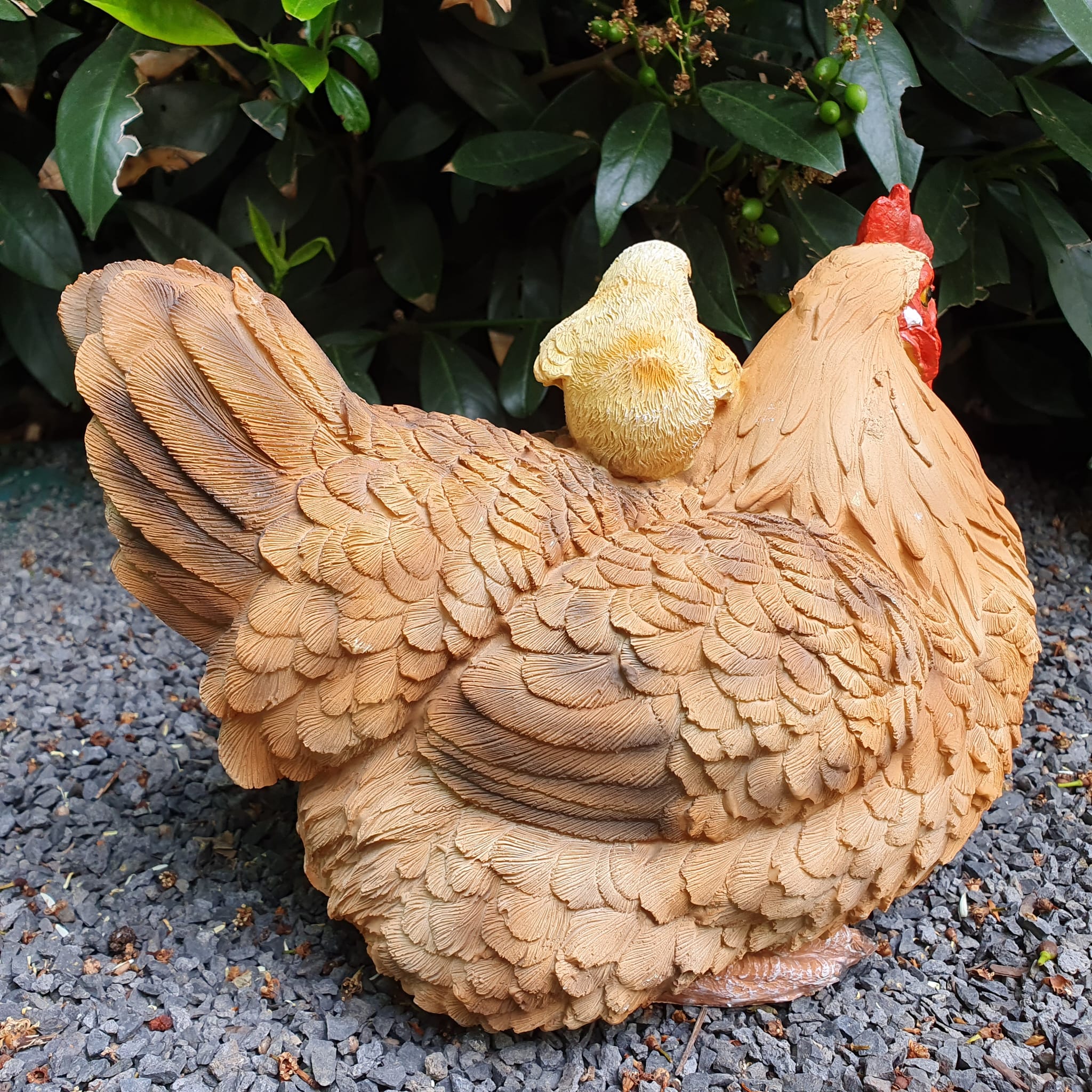 Sitzende braune Hühner Gartenfigur mit verspielten gelben Küken von hinten