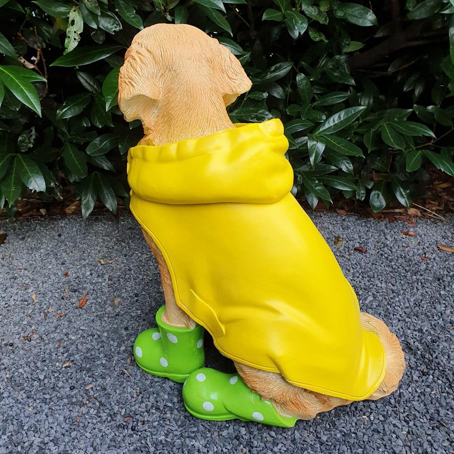 Heller Labrador in Gelben Mantel und Grünen Schuhen als Gartenfigur von hinten