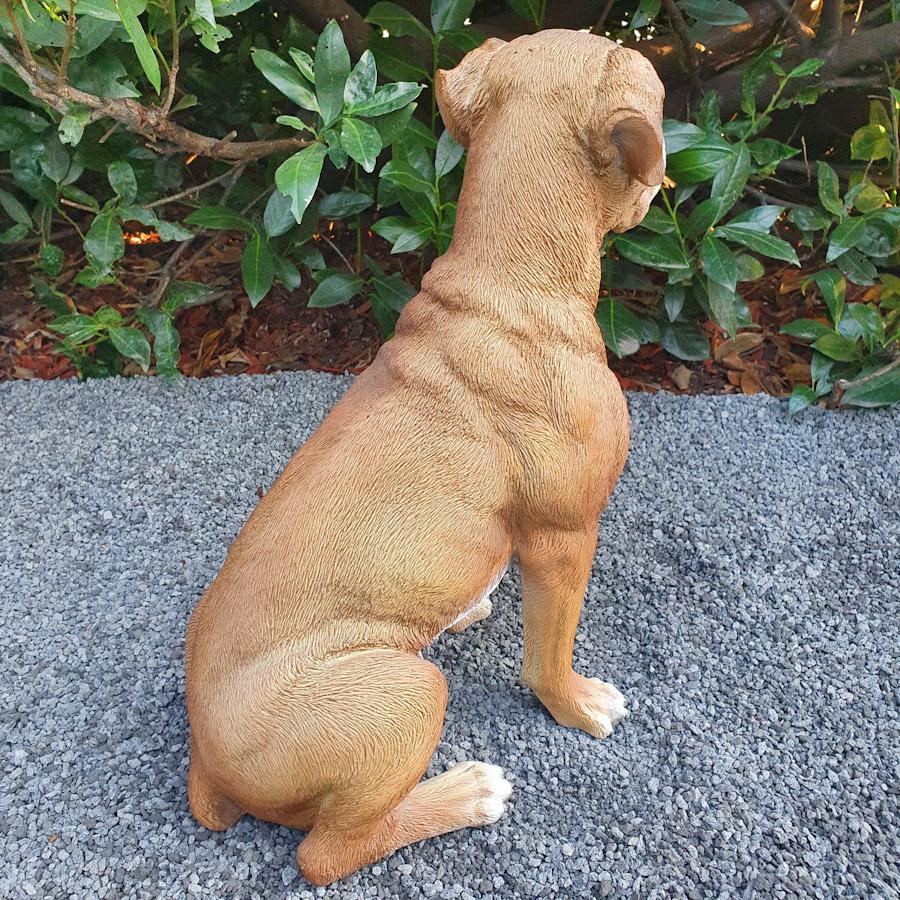Braune Doge als Gartenfigur von hinten