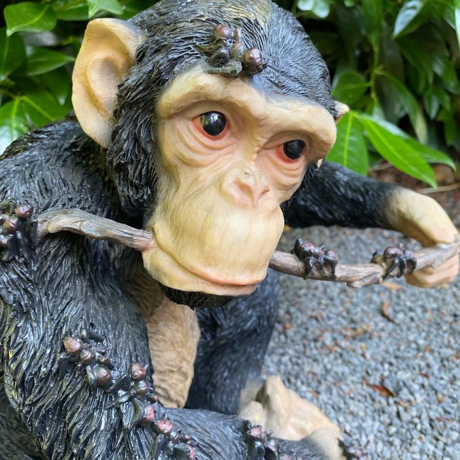 Schimpanse mit Stock im Mund als Gartenfigur Nahaufnahme