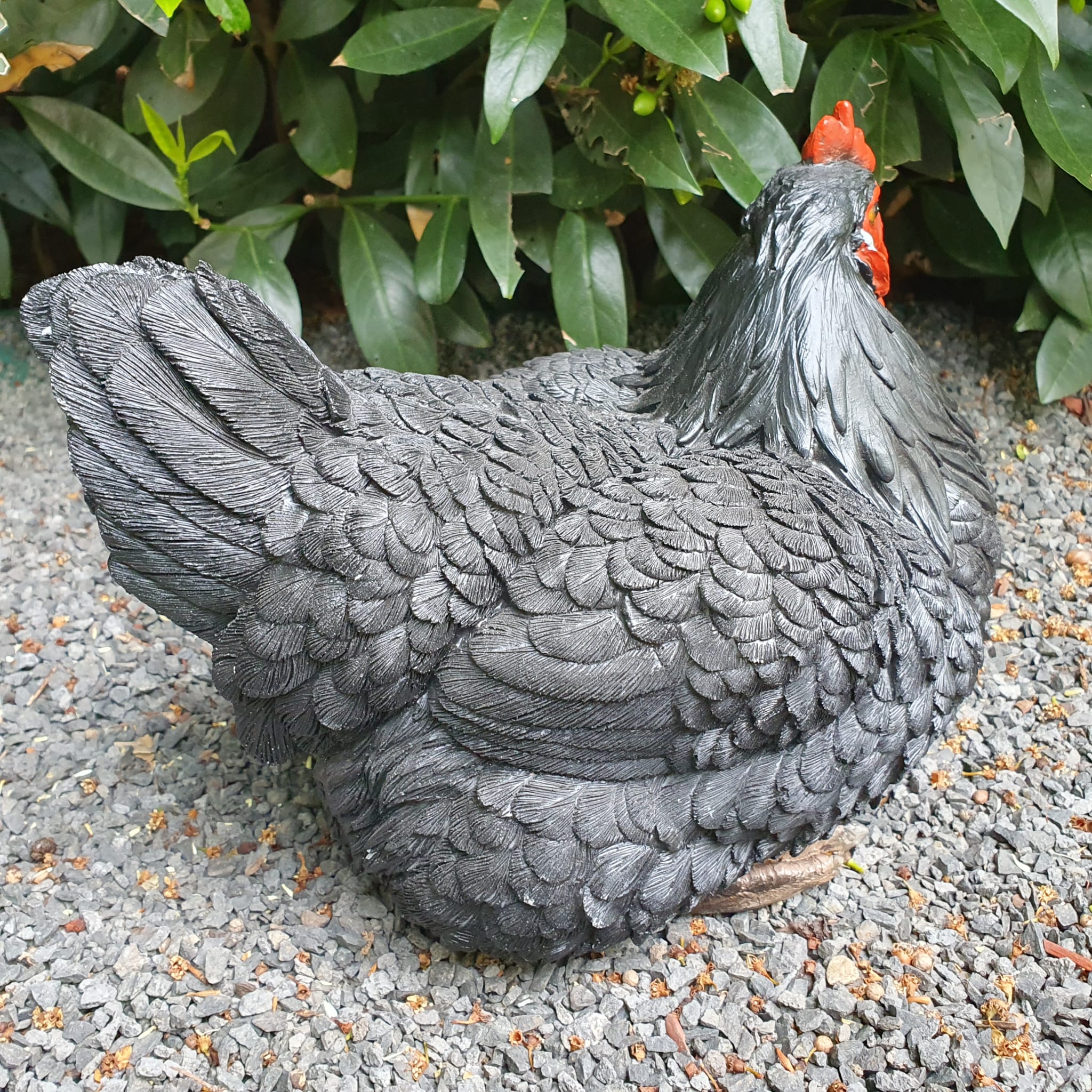 Schwarze sitzende Hühner Gartenfigur von hinten