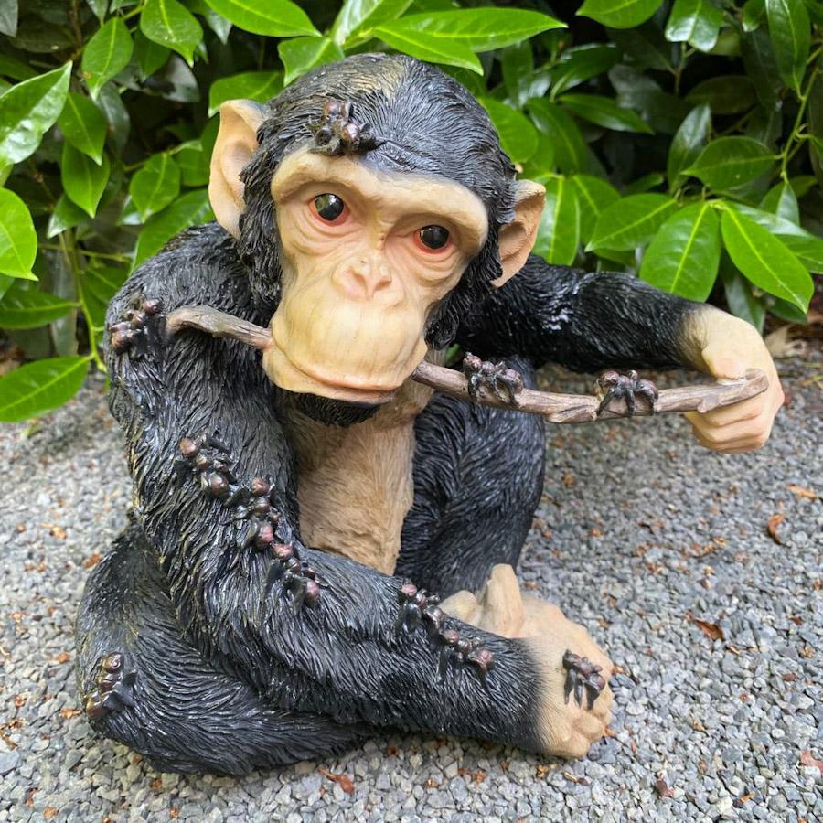 Schimpanse mit Stock im Mund als Gartenfigur